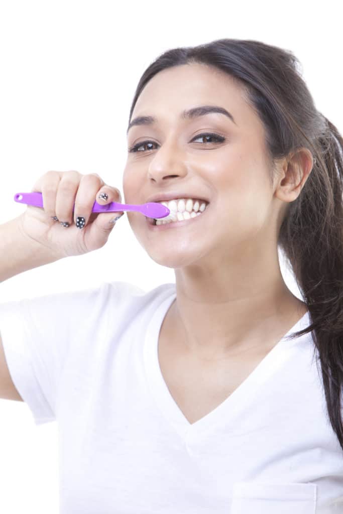 Portrait of young attractive woman brushing her teeth